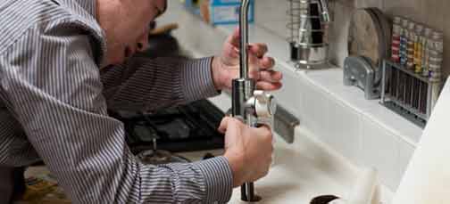 A plumber working on something that causes water leaks.