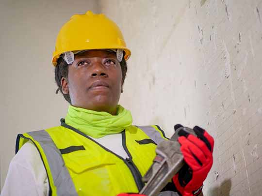 A handywoman is holding a plumber’s wrench