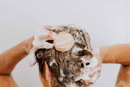 A woman washing her hair with soap.