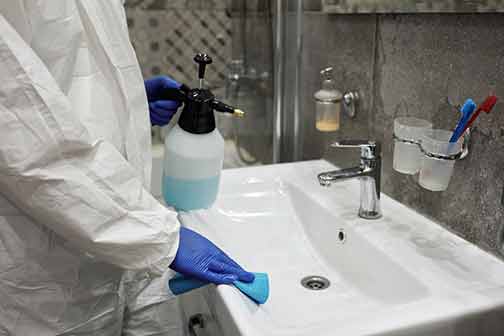 A professional cleaning the bathroom sink.