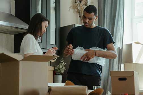 Couple packing items using bubble wrap.