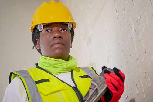 Handywoman holding a plumber wrench.