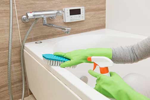 a woman cleaning her bathtub.