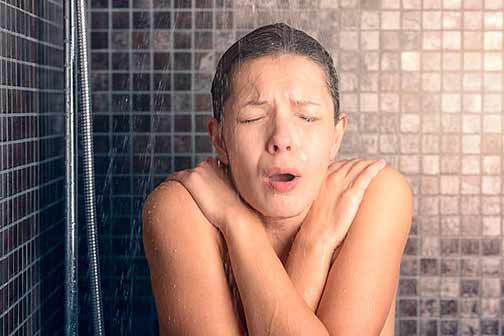 a woman with cold water in her shower.