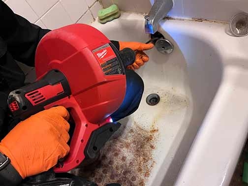 a plumber cleaning out sewage backup in a tub.