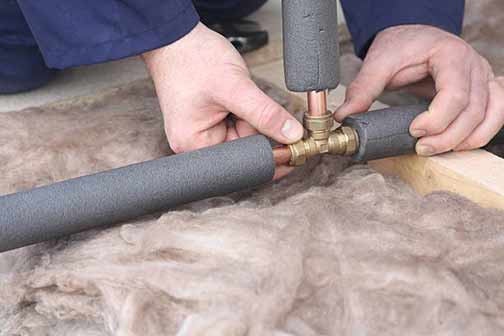 a man insulating his pipes before winter