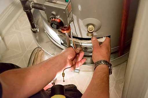 a plumber re-lighting a water heater pilot light.