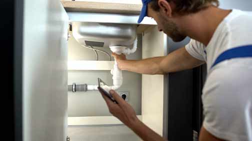 a plumber performing an inspection on pipes.