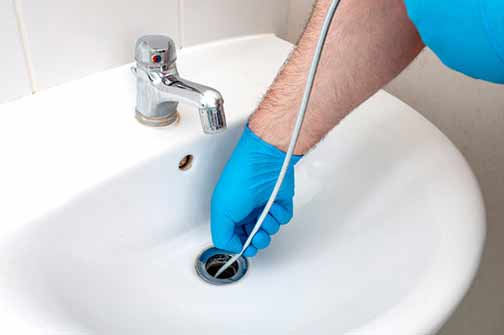 a person using a plumbing snake 