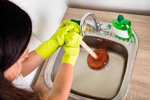 a woman plunging her bathroom sink.