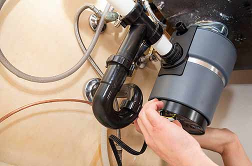 a person repairing a garbage disposal.