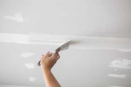 a woman repairing her ceiling bubbles.