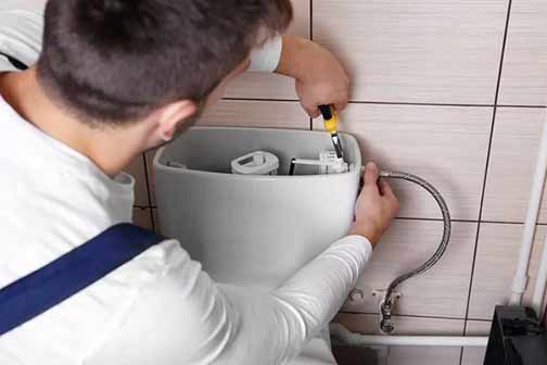 a man replacing his water supply line on toilet.