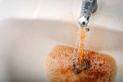 a sink shooting out rust colored water.