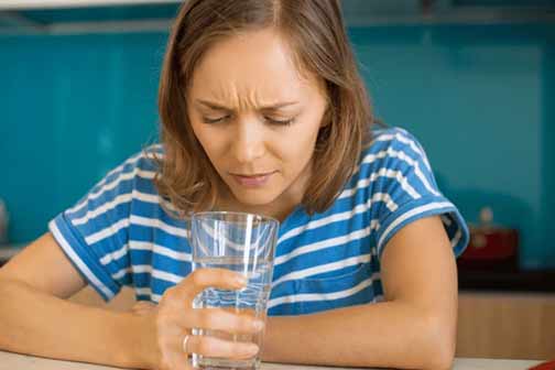 a woman that has smelly water in her glass.