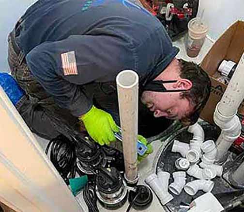 a plumber performing a sump pump repair