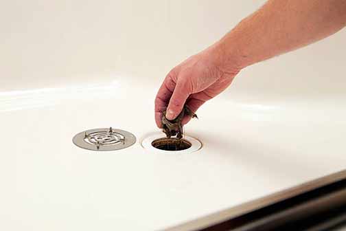 a man unclogging a shower drain.