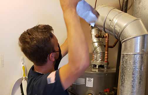 a plumber performing water heater maintenance.